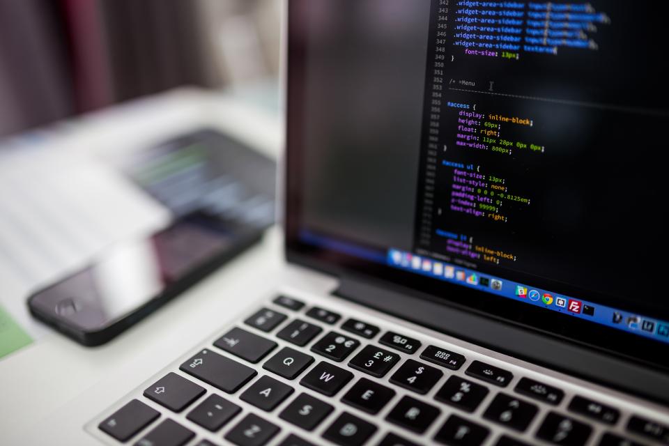 Laptop open to a code editor, with a phone beside the keyboard