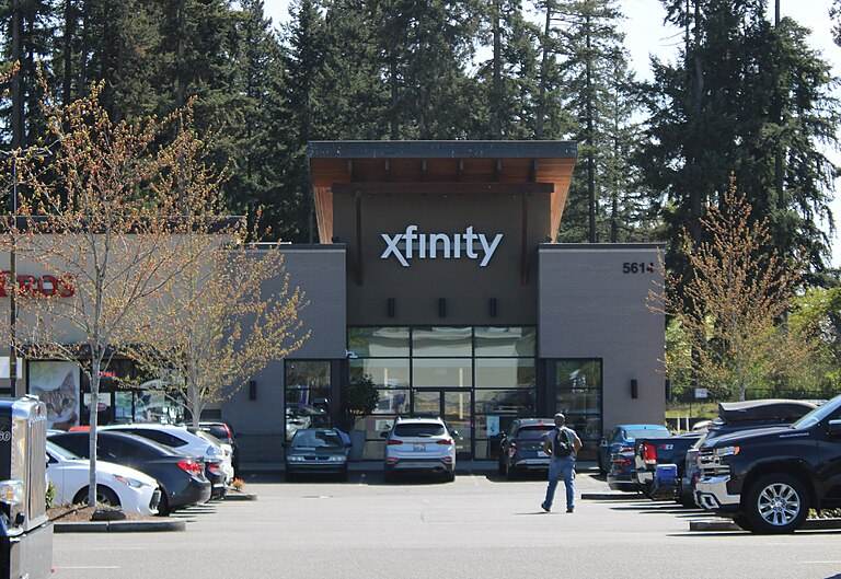 The front of an Xfinity retail store, a low brick building with the Xfinity logo above glass doors and cars parked outside
