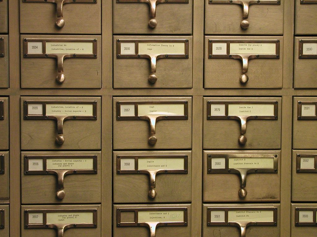 Numbered card catalog drawers with typed labels in brass holders at a university library