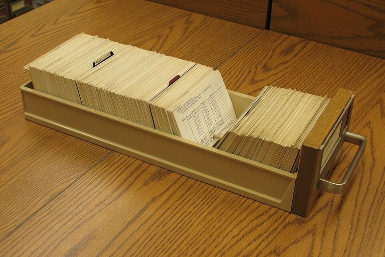 An open card-catalog drawer packed with typed index cards and tab dividers, resting on a wooden table at the Library of Congress